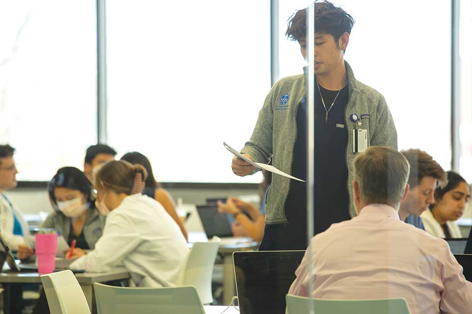 Student standing and reading a paper he wrote to the class Student standing and reading a paper he wrote to the class